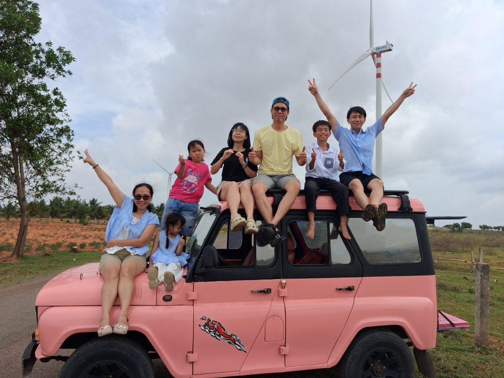 Group of travelers who book Mui Ne Jeep Tour direct posing on colorful Jeeps