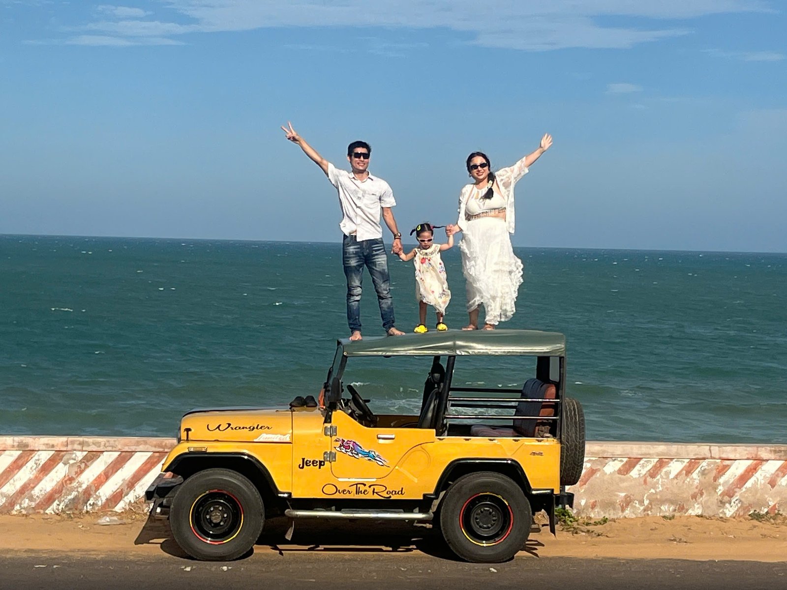 gia đình trẻ chụp ảnh bên bờ biển với jeep vàng