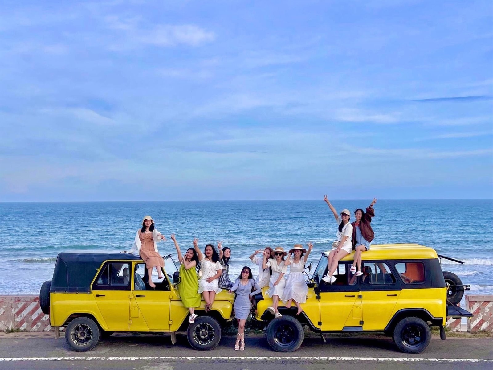 group of traveller take photo at coastal road with yellow jeep